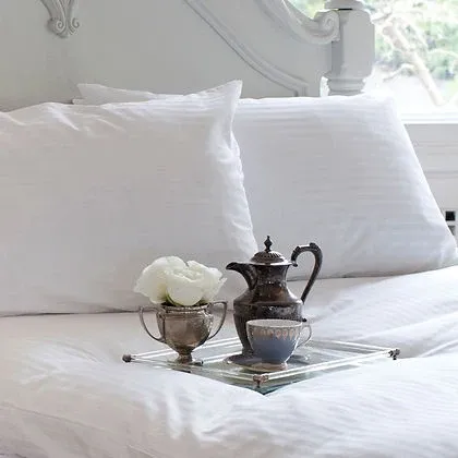 Luxury white bed with pillows and silver tea tray, styled with St. Genève Luxury Topper Protector