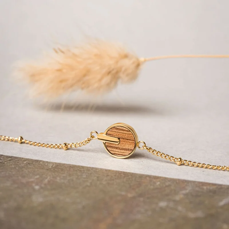 Armband mit runder Holzscheibe, goldfarbener Kette und hellem Flauschelement
