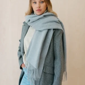 Luxuriously soft TBCo Lambswool Oversized Scarf in Light Grey Melange draped stylishly over a grey winter coat, showcasing fringed detail