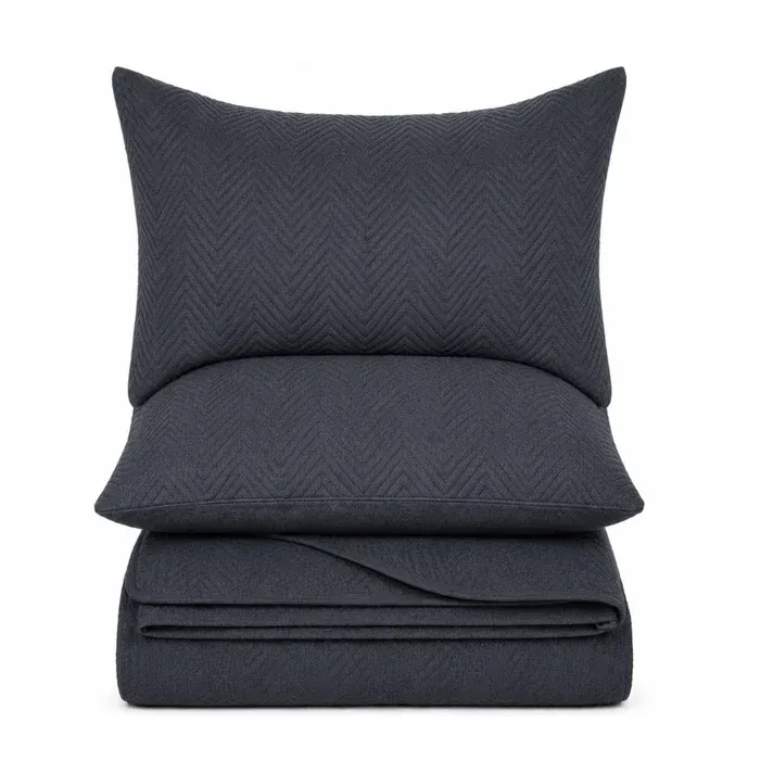 A dark navy blue bedding set featuring a pillowcase, a folded sheet or duvet cover, and a matching folded pillow, all with a subtle textured chevron pattern, shown against a plain white background.