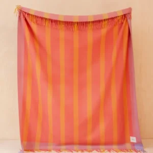 TBCo Recycled Wool Blanket in Orange Frame Stripe hanging with delicate fringed edges against pale wooden wall