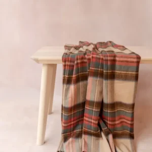 Cashmere Small Blanket in Stewart Dress Antique Tartan by TBCo draped over a light wooden bench with soft fringe detail