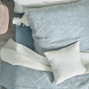 Leitner Valdera firm decorative pillow in ivory on blue damask bedding.