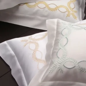 Dea Diana white cotton pillowcases with gold and sage laurel wreath embroidery.