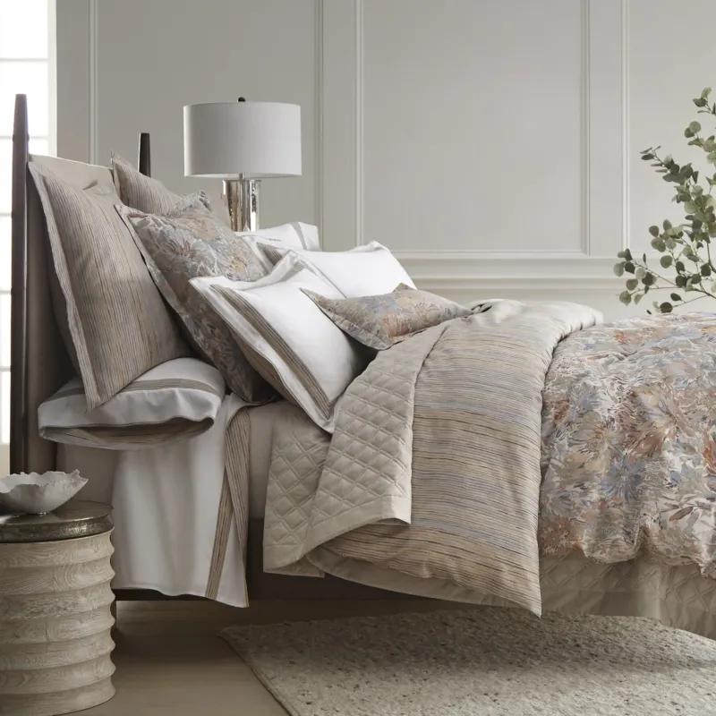 Home Treasures Gaia quilted coverlet in ivory with floral euro shams on styled bed.