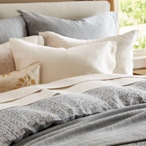 SDH Milos Linen ruffled bedskirt in ivory styled on a bed with layered linens.