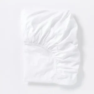 Coyuchi Cloud Soft Sateen fitted sheet in white, folded flat showing elasticized corners.