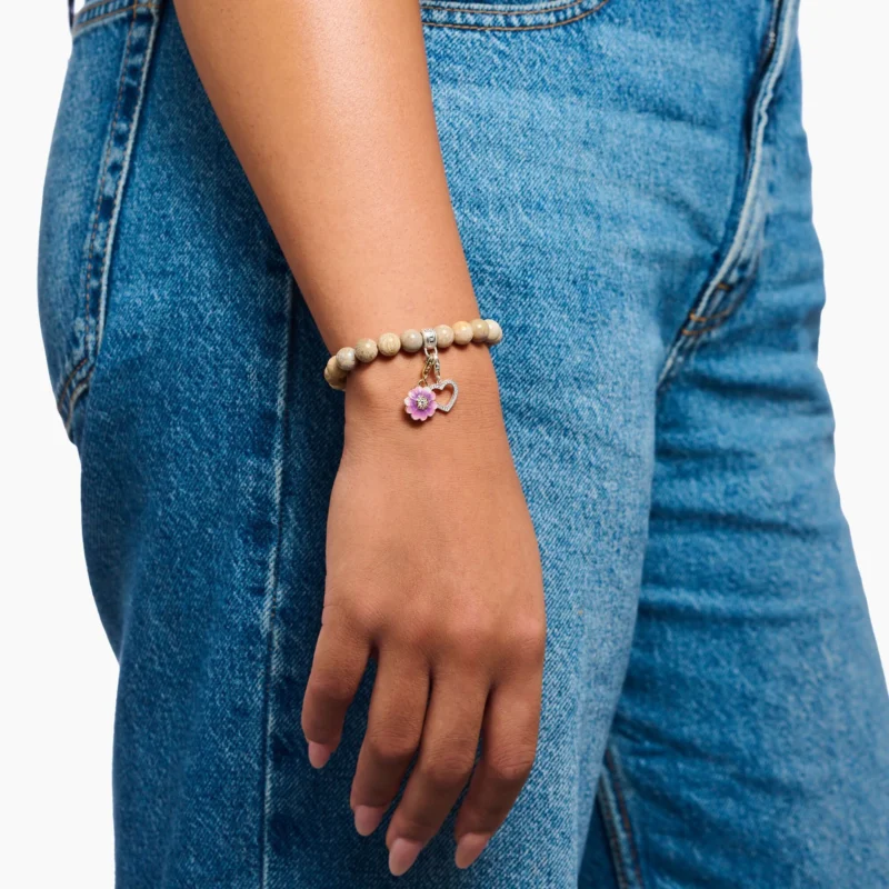 Perlenarmband am Handgelenk mit hellbeigen Perlen und Charm-Öse